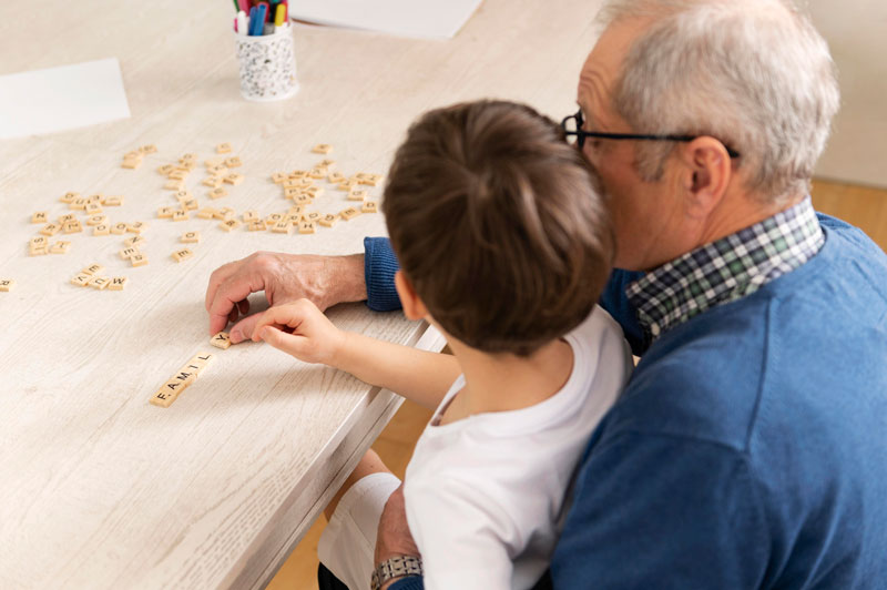 Hombre mayor jugando con su nieto al Scrabble